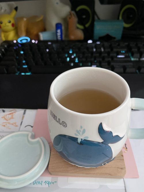 A mug with an open lid and a whale on the body